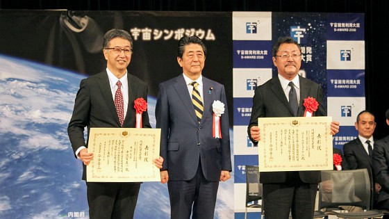 安倍総理（中央）から表彰状を受け取った東京大学の中須賀教授（左）とほどよしプロジェクトチーム（右）